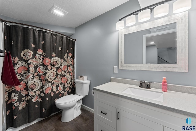 bathroom with wood finished floors, toilet, vanity, a textured ceiling, and baseboards