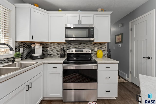 kitchen with appliances with stainless steel finishes, a sink, and white cabinetry