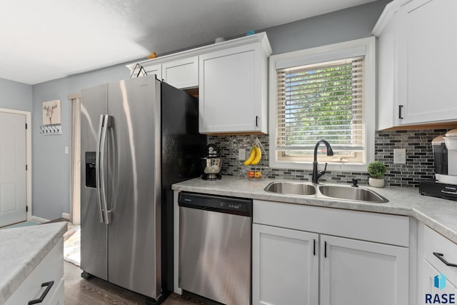 kitchen with stainless steel appliances, a sink, decorative backsplash, white cabinets, and light countertops
