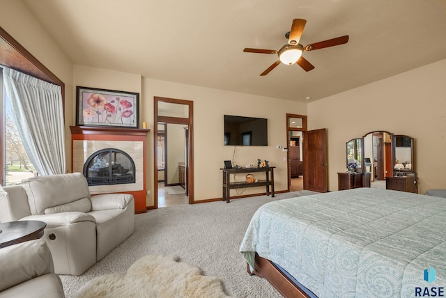 bedroom featuring carpet floors, a tile fireplace, baseboards, and ceiling fan