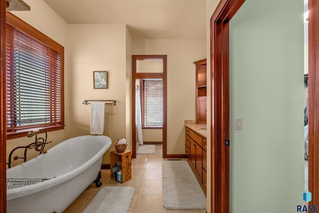bathroom with healthy amount of natural light, a freestanding bath, tile patterned floors, and baseboards