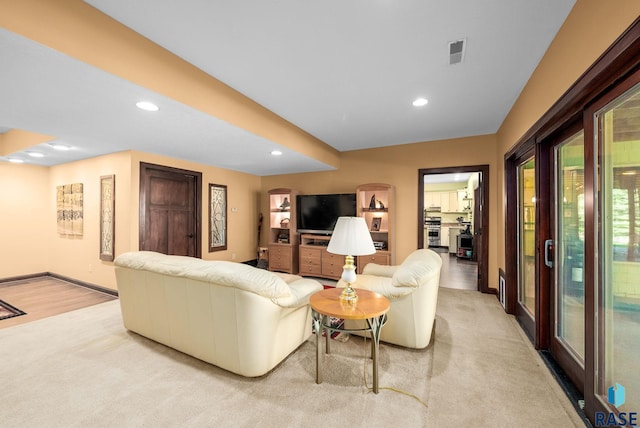 living area with recessed lighting, light carpet, and baseboards