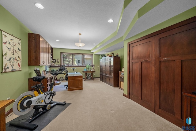 exercise room featuring light colored carpet, recessed lighting, and a textured ceiling