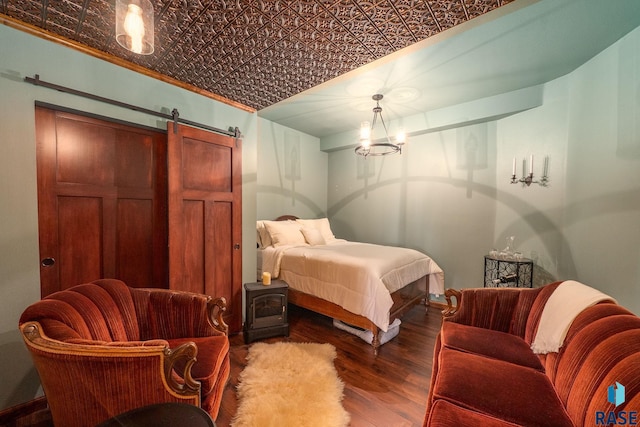 bedroom featuring an ornate ceiling, wood finished floors, a barn door, and baseboards