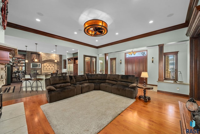 living room featuring wood finished floors, crown molding, decorative columns, baseboards, and recessed lighting