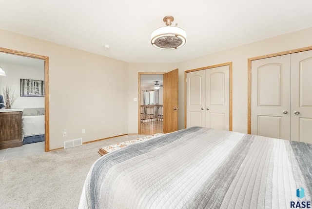 carpeted bedroom with multiple closets, connected bathroom, and baseboards