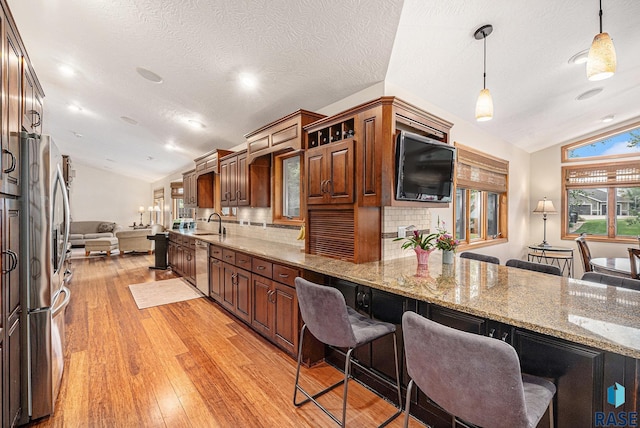 711 Britz Dr, Luverne, MN 56156 - kitchen featuring vaulted ceiling, stainless steel appliances, light wood-type flooring, open floor plan, and a kitchen breakfast bar