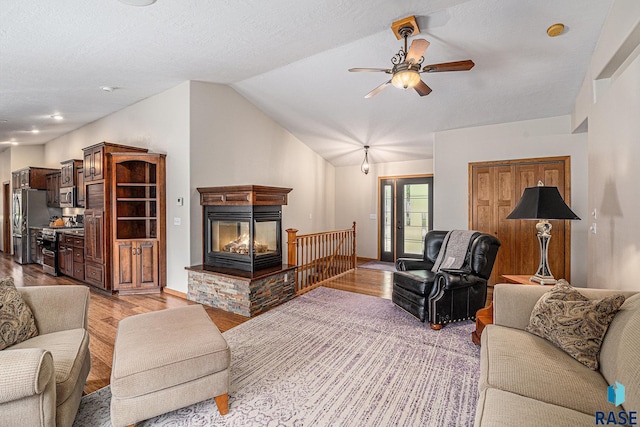 711 Britz Dr, Luverne, MN 56156 - living room featuring light wood finished floors, a ceiling fan, vaulted ceiling, and a multi sided fireplace