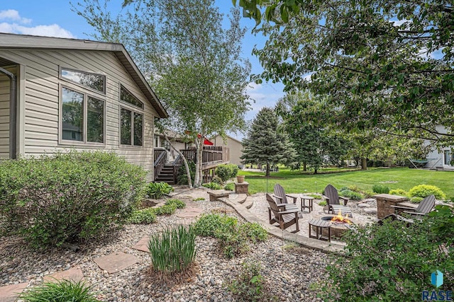 711 Britz Dr, Luverne, MN 56156 - view of grassy yard featuring an outdoor fire pit, a wooden deck, stairs, and a patio area