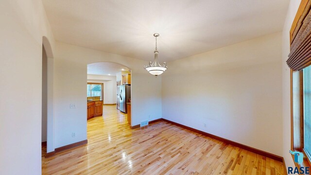 851 Regency Ct, Brookings, SD 57006 - empty room with arched walkways, light wood-type flooring, and baseboards