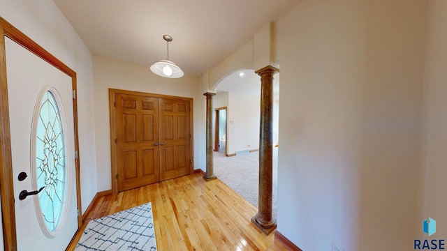 851 Regency Ct, Brookings, SD 57006 - foyer entrance featuring decorative columns, arched walkways, light wood-style floors, and baseboards