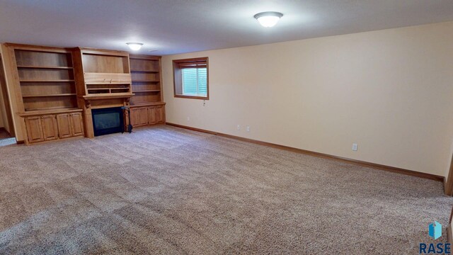 851 Regency Ct, Brookings, SD 57006 - unfurnished living room with a glass covered fireplace, light carpet, and baseboards