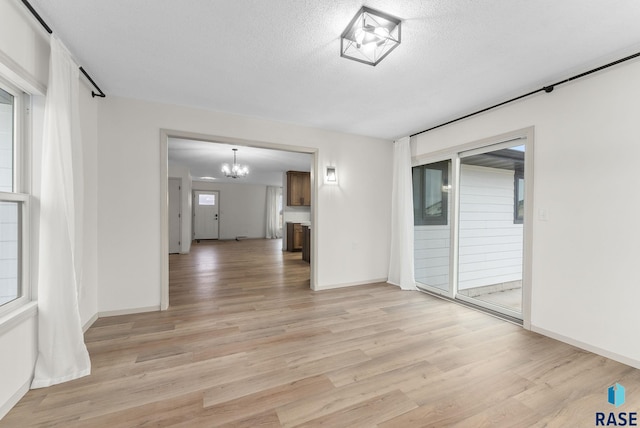 1335 Blue Ox St, Harrisburg, SD 57032 - unfurnished living room featuring a chandelier, light wood finished floors, a textured ceiling, and baseboards