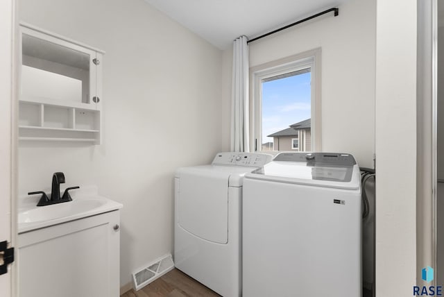 1335 Blue Ox St, Harrisburg, SD 57032 - laundry room featuring independent washer and dryer, wood finished floors, cabinet space, and baseboards