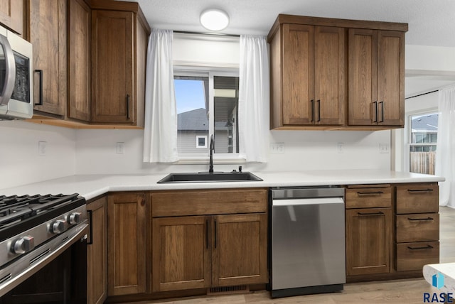1335 Blue Ox St, Harrisburg, SD 57032 - kitchen with appliances with stainless steel finishes, a sink, light wood finished floors, and light countertops
