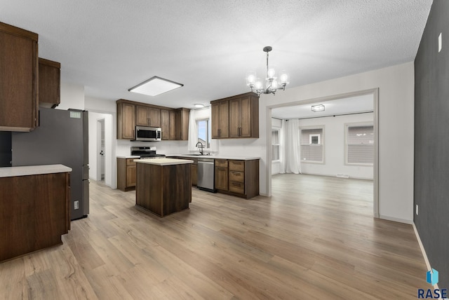 1335 Blue Ox St, Harrisburg, SD 57032 - kitchen with appliances with stainless steel finishes, a sink, a kitchen island, light wood-type flooring, and a chandelier