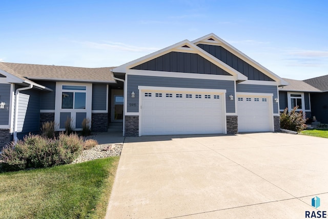 view of front of property with a garage, board and batten siding, stone siding, driveway, and roof with shingles