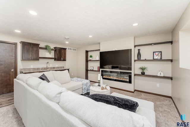 living room with baseboards, light carpet, a glass covered fireplace, recessed lighting, and wet bar