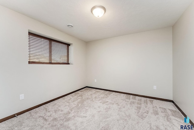 empty room featuring carpet and baseboards