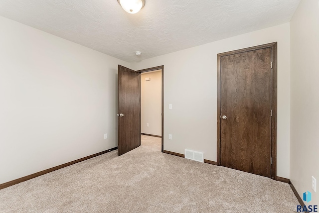 unfurnished bedroom with light carpet, baseboards, and a closet