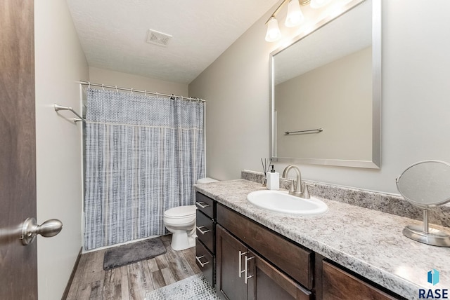 full bathroom featuring wood finished floors, vanity, toilet, and curtained shower