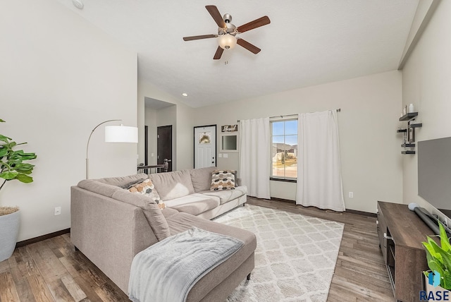 living area featuring vaulted ceiling, ceiling fan, wood finished floors, and baseboards