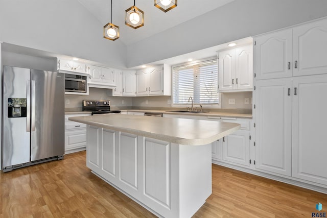 kitchen with appliances with stainless steel finishes, a sink, light countertops, light wood finished floors, and white cabinetry