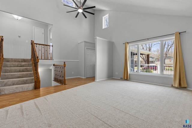unfurnished living room featuring carpet flooring, a ceiling fan, high vaulted ceiling, baseboards, and stairs