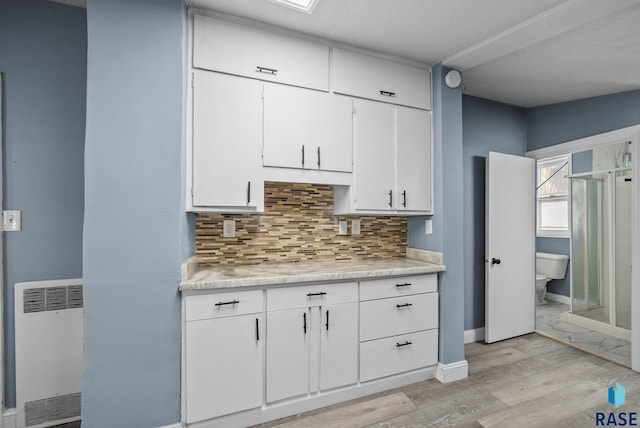 kitchen featuring light countertops, decorative backsplash, white cabinetry, and light wood finished floors