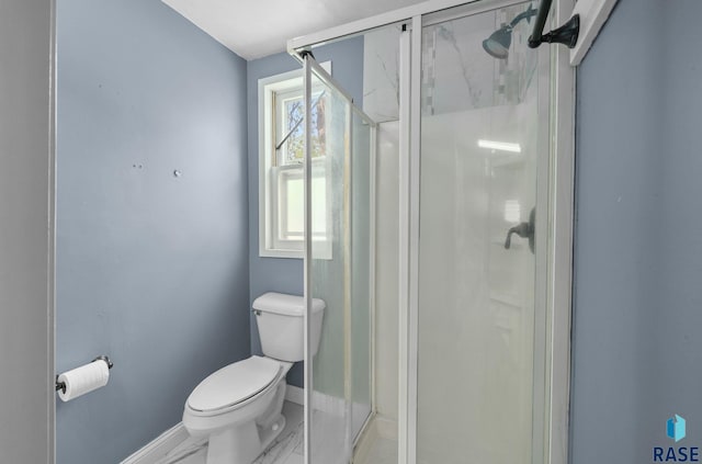 bathroom featuring baseboards, toilet, and a shower stall