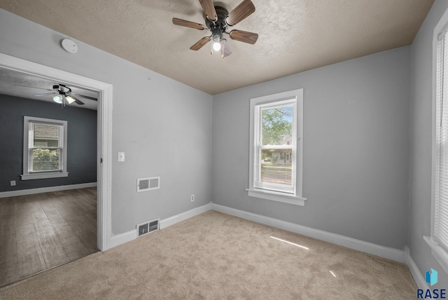 carpeted spare room with ceiling fan, baseboards, a textured ceiling, and a smoke detector