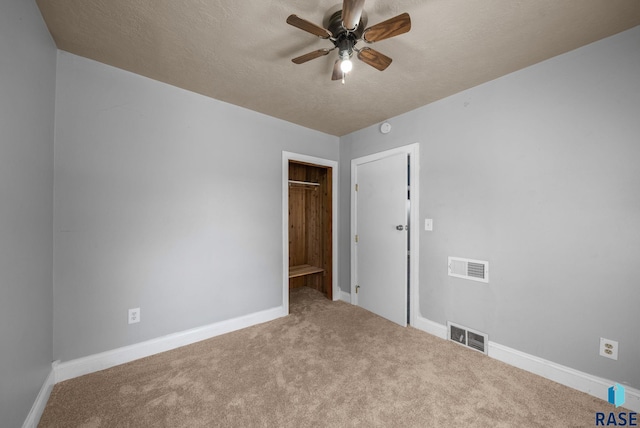 carpeted spare room featuring ceiling fan, baseboards, and a textured ceiling