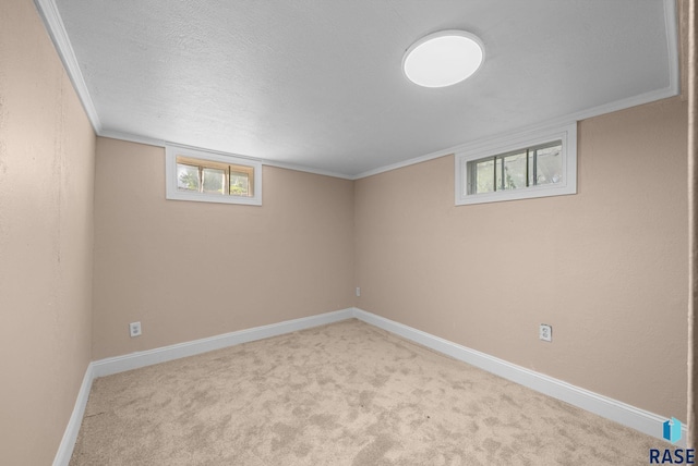 below grade area featuring carpet, healthy amount of natural light, baseboards, ornamental molding, and a textured ceiling