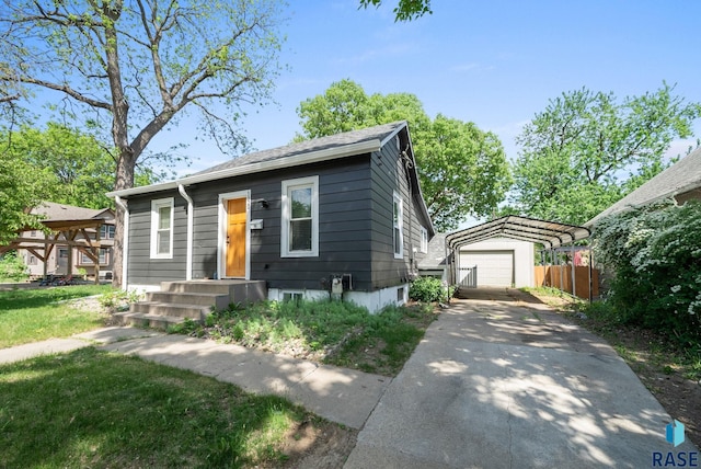 view of front of property featuring an outdoor structure, fence, driveway, and a detached garage