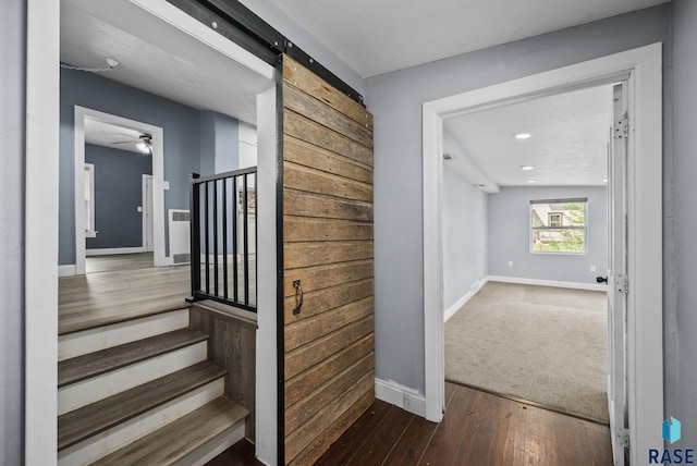 stairs featuring baseboards, wood-type flooring, recessed lighting, a ceiling fan, and a barn door