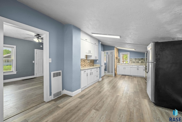 kitchen with freestanding refrigerator, tasteful backsplash, white cabinetry, plenty of natural light, and lofted ceiling