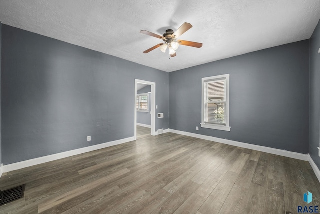 empty room with a ceiling fan, a textured ceiling, wood finished floors, and baseboards