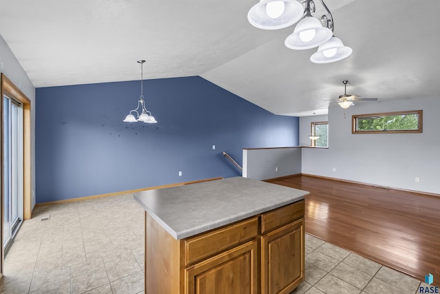 kitchen with a chandelier, lofted ceiling, a ceiling fan, a kitchen island, and light tile patterned flooring