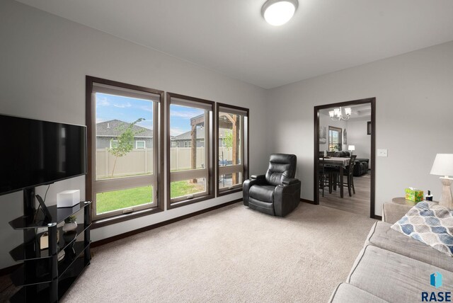 living area with carpet floors, healthy amount of natural light, and a chandelier