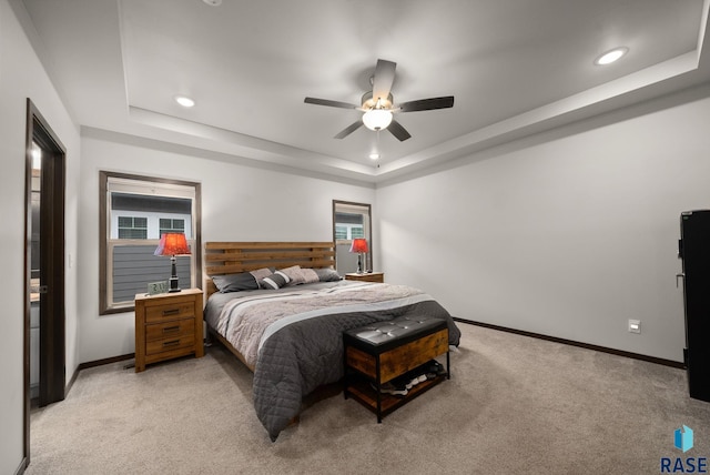 bedroom featuring light carpet, a tray ceiling, baseboards, recessed lighting, and a ceiling fan