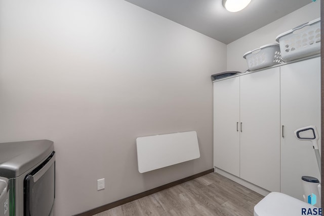 laundry area with cabinet space, light wood finished floors, washer and clothes dryer, and baseboards