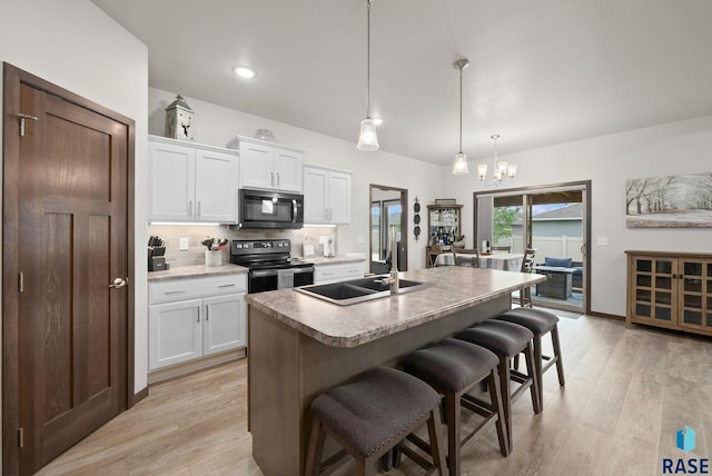 kitchen featuring electric range, a breakfast bar, a chandelier, white cabinetry, and a sink