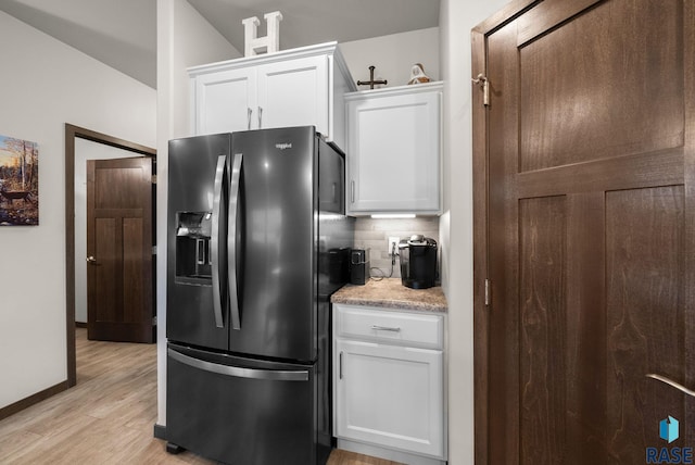 kitchen featuring black fridge with ice dispenser, tasteful backsplash, white cabinets, light wood-style flooring, and baseboards
