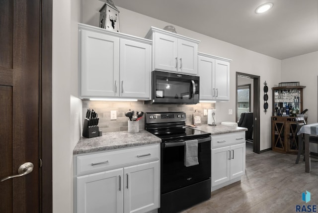 kitchen featuring black electric range oven, tasteful backsplash, and white cabinets