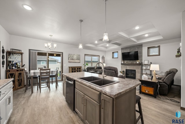 kitchen with a sink, stainless steel dishwasher, light wood finished floors, a fireplace, and recessed lighting