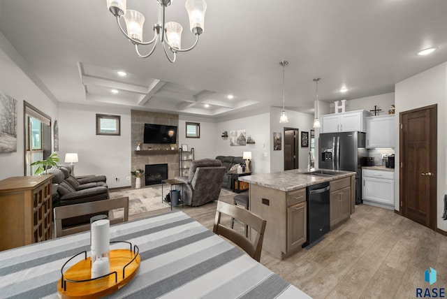 dining space featuring light wood-type flooring, coffered ceiling, a tile fireplace, recessed lighting, and a chandelier