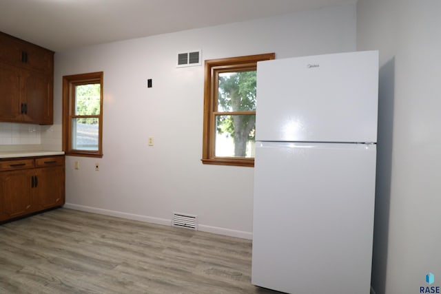 kitchen featuring freestanding refrigerator, light wood-style floors, and baseboards