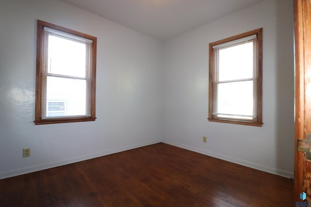 empty room with plenty of natural light, dark wood-style flooring, and baseboards