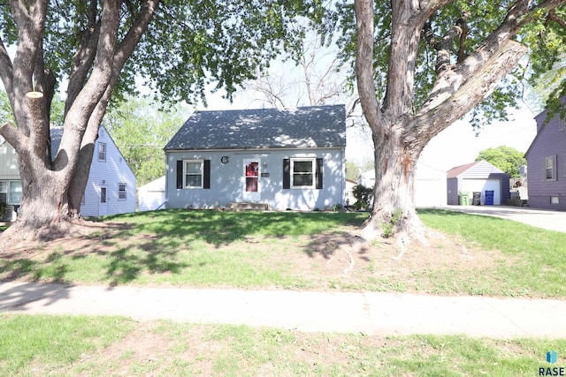 view of front facade with a front yard, a garage, roof with shingles, and stucco siding