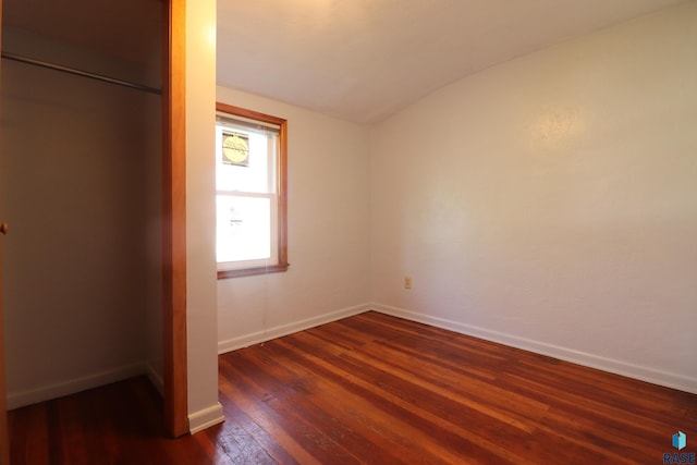 unfurnished bedroom featuring lofted ceiling, dark wood-style floors, and baseboards